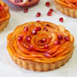 Close up of a Persimmon Almond Rosette Tart sprinkled with pomegranates.