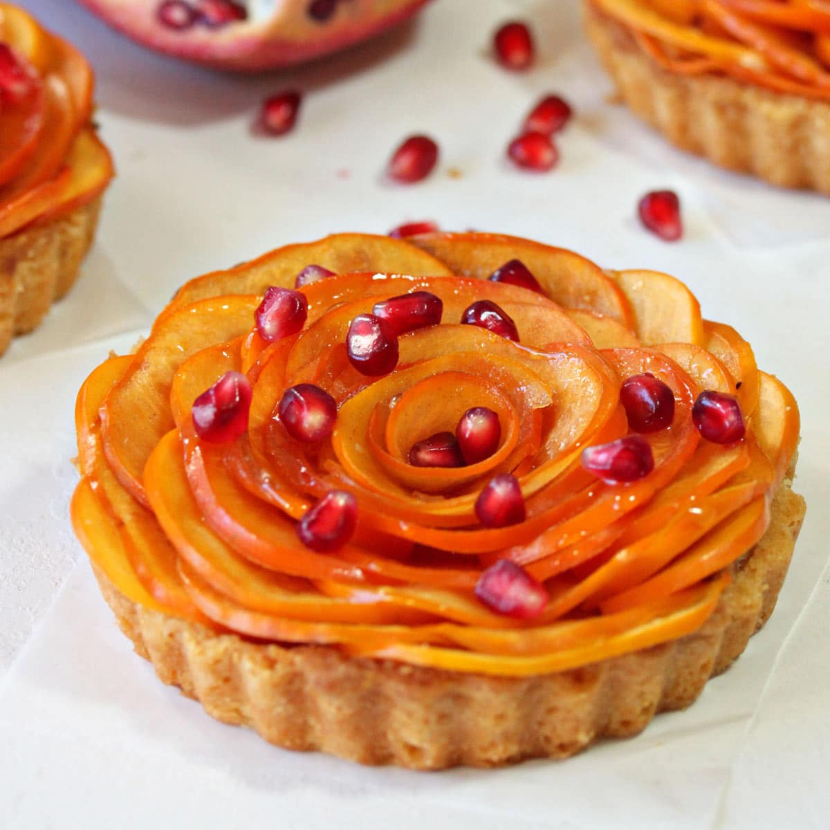 Close up of a Persimmon Almond Rosette Tart sprinkled with pomegranates.