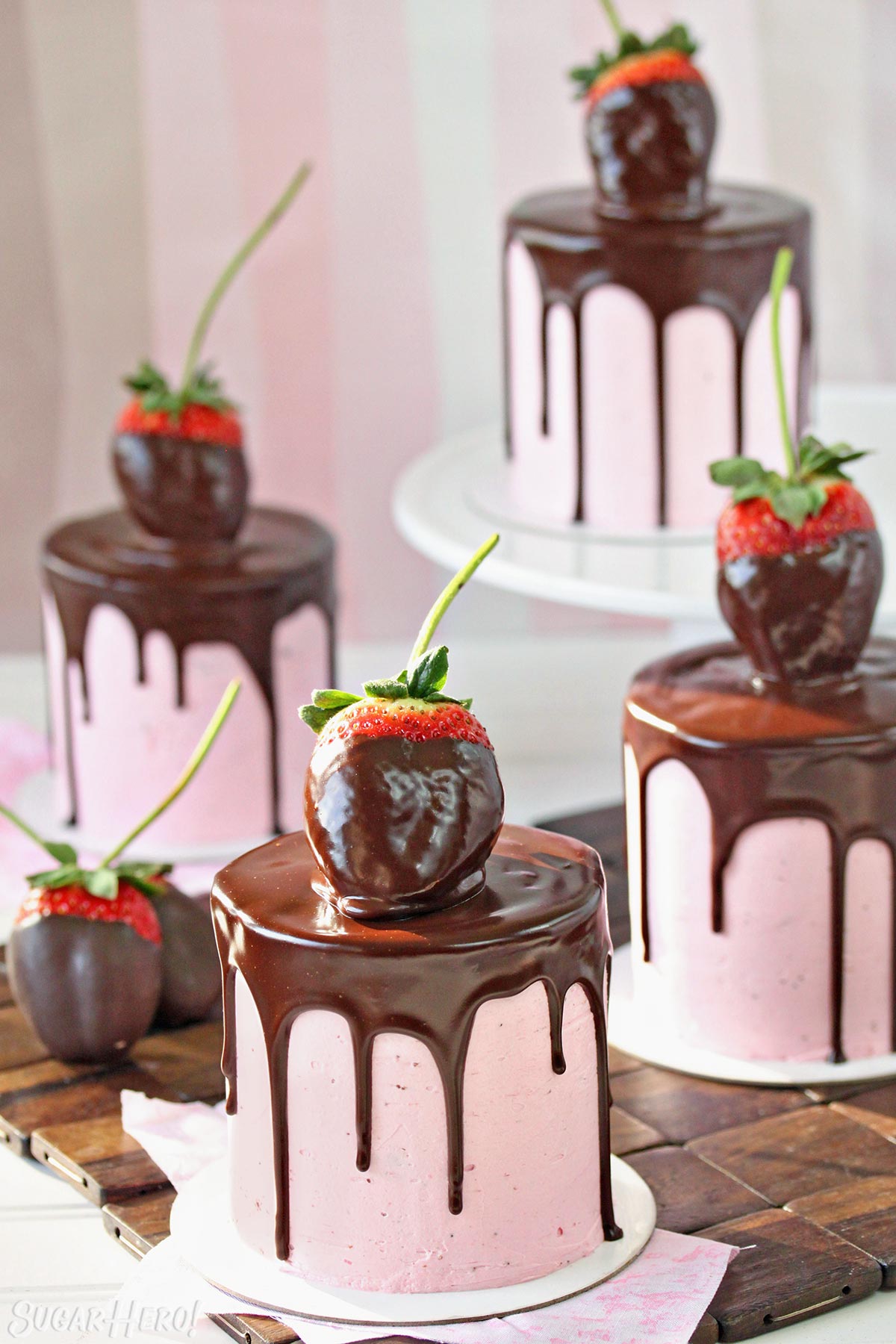 Chocolate-Covered Strawberry Cakes - Four separate cakes with chocolate dripping down the sides, and chocolate covered strawberry's on top. | From SugarHero.com