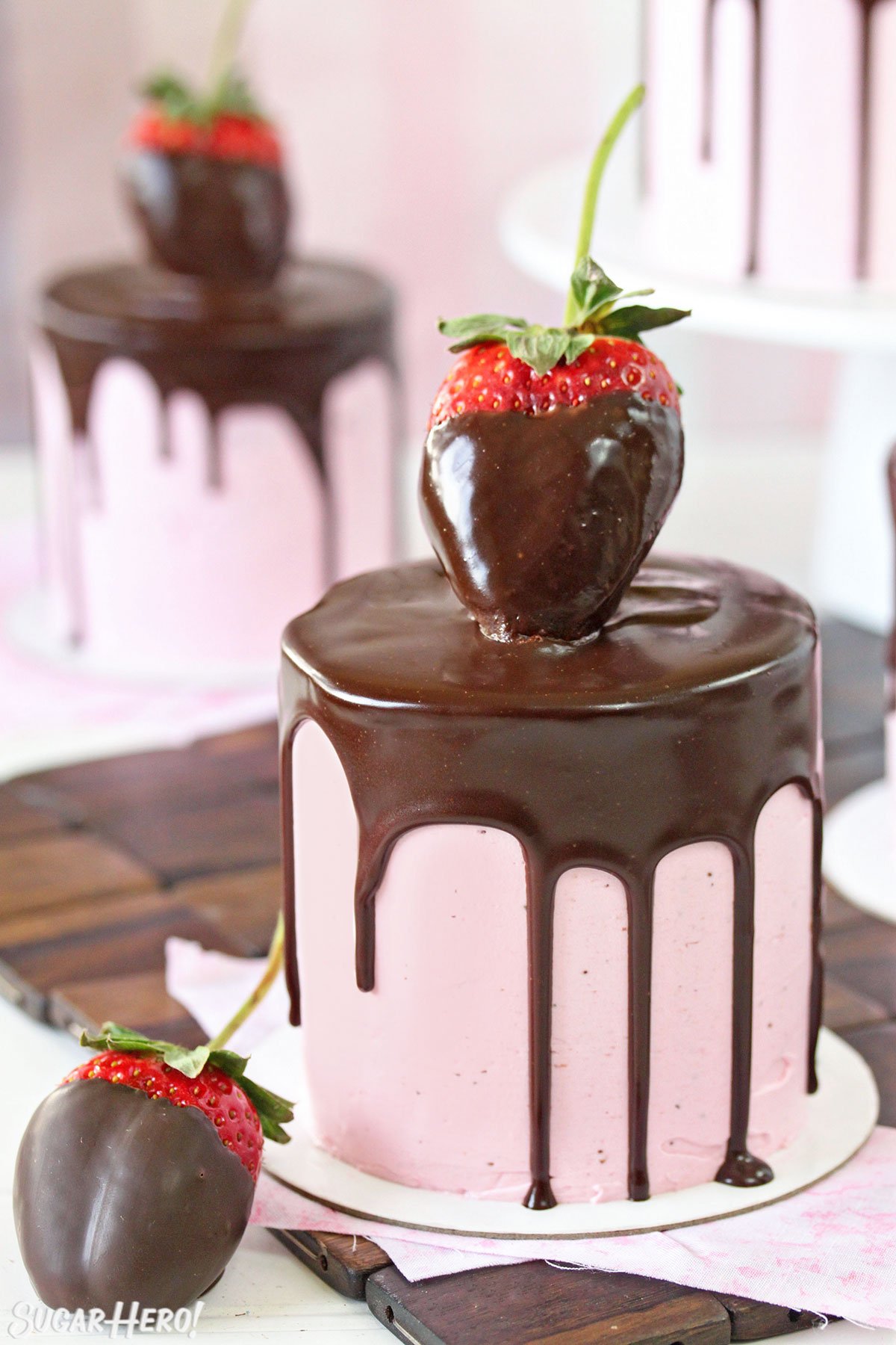 Chocolate-Covered Strawberry Cakes - A single cake displayed with a chocolate strawberry on the top and one to the side. | From SugarHero.com