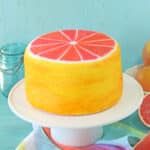 Grapefruit Layer Cake on a white cake platter with an aqua colored background.