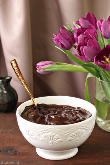 A bowl of ganache with purple tulips in the background.