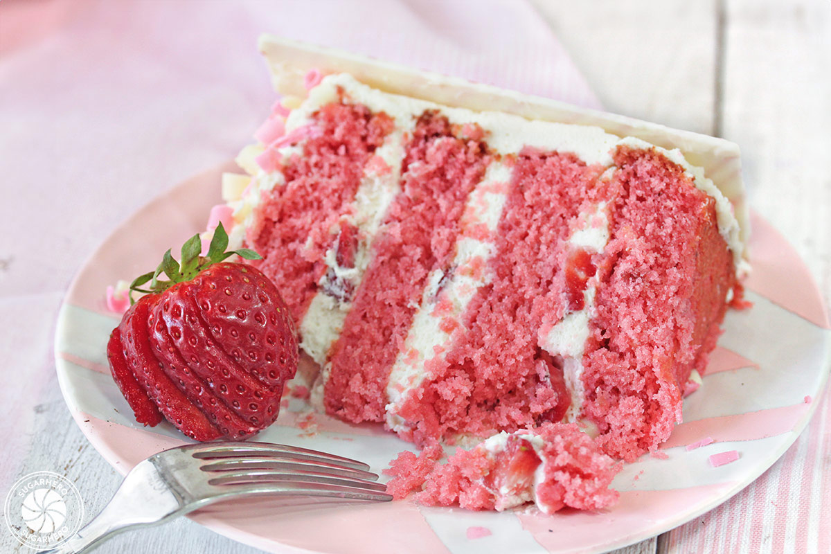 Strawberries and Cream Layer Cake - close-up of a single slice of strawberry cake with a bite taken out of it | From SugarHero.com