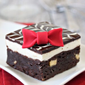 Close up of a Tuxedo Brownie on white plate with a fondant bowtie.