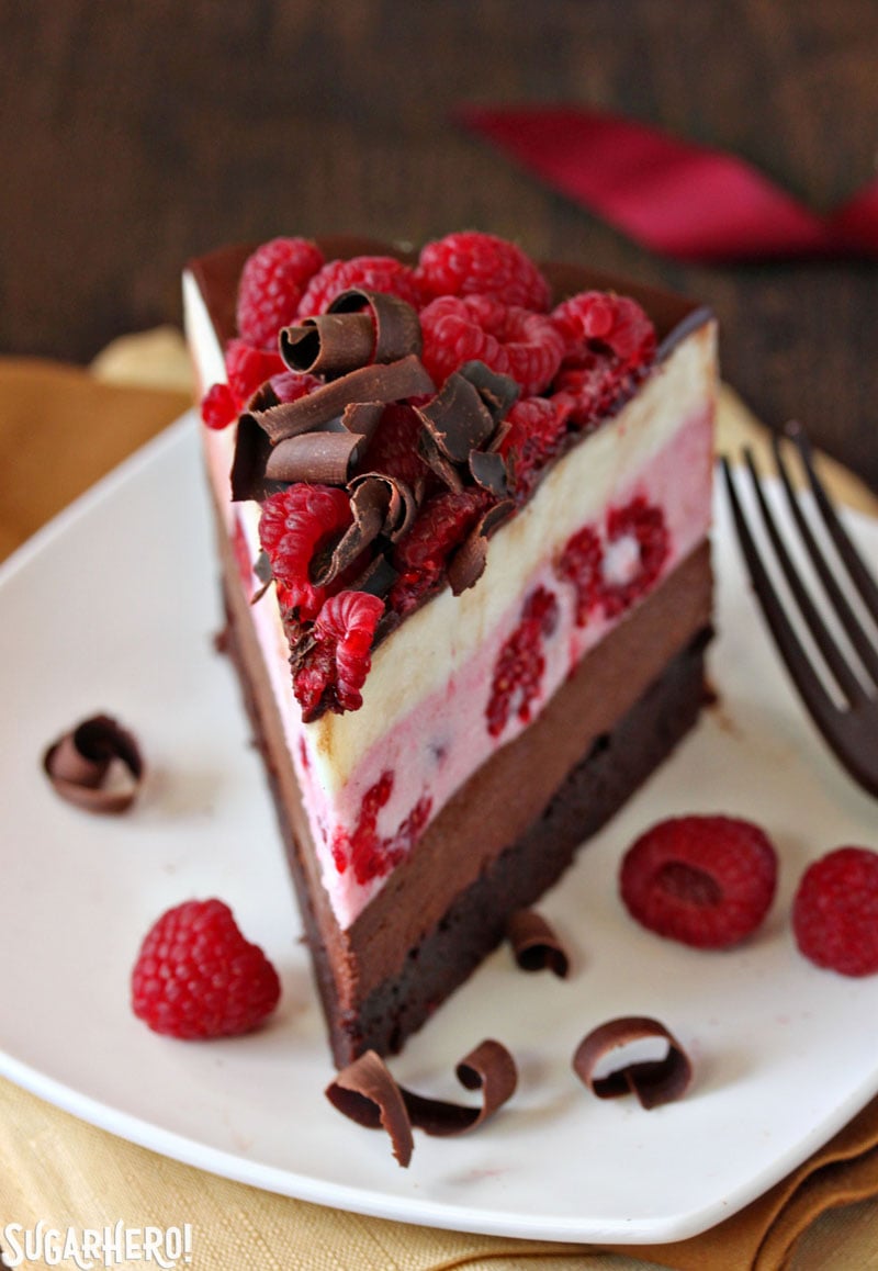 Chocolate Raspberry Mousse Cake - A close up shot of a piece of the mousse cake displayed on plate with raspberries on top. | From SugarHero.com