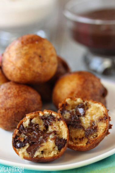 Deep Fried Chocolate Chip Cookie Dough balls on a white plate with one cut open to show the inside.
