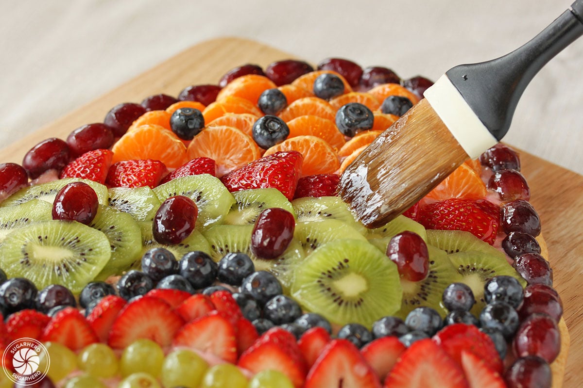 Pastry brush brushing apricot glaze on Easter Egg Fruit Pizza