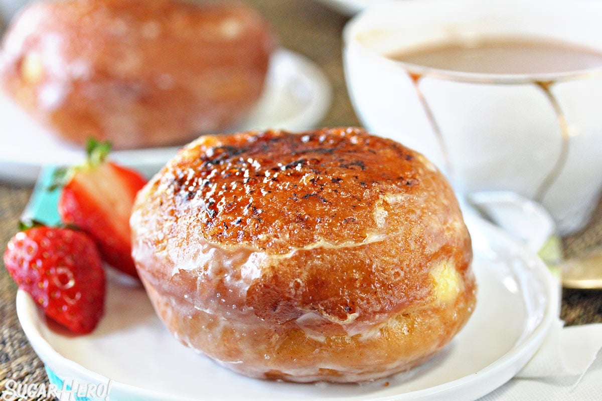 Close-up of a Crème Brûlée Donut on a white plate with more donuts in the background.