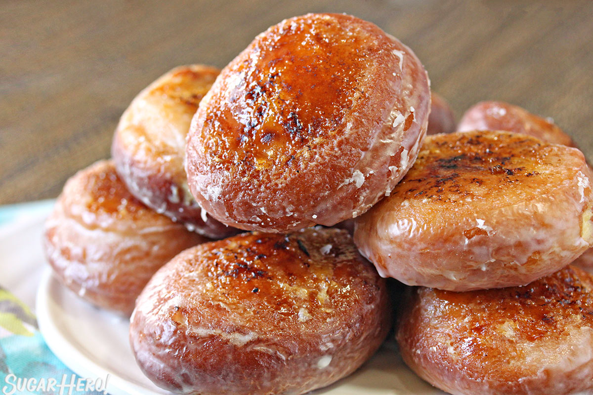 Stack of Crème Brûlée Donuts with caramelized sugar crusts, on a white plate.