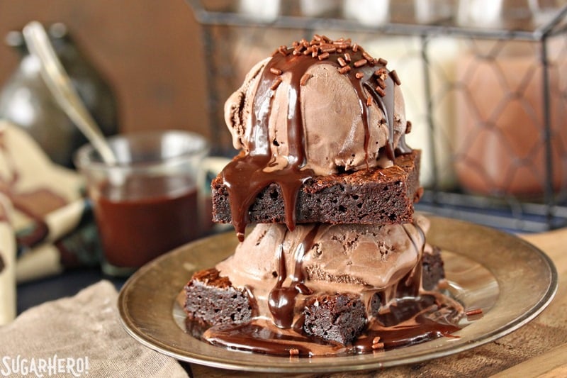 Ultimate Fudgy Chocolate Brownies - close-up of brownies topped with chocolate ice cream and dripping chocolate fudge sauce | From SugarHero.com