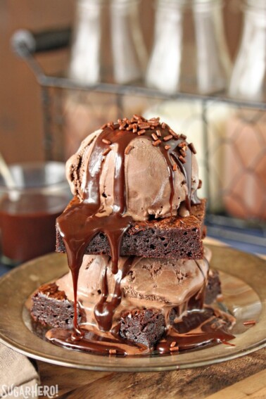 2 Ultimate Fudgy Chocolate Brownies stacked between scoops of chocolate ice cream, hot fudge and sprinkles.