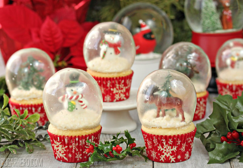 Seven cupcakes with gelatin globes on top, encasing toy figurines inside the globes.