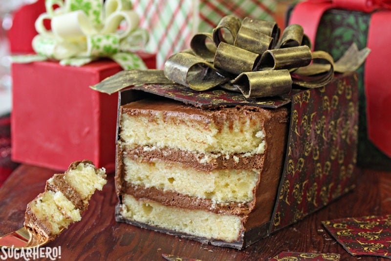 Layered cake wrapped in a chocolate wrapping with a gold edible bow on top.