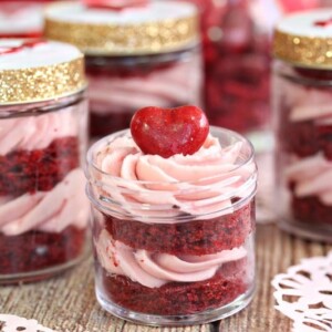 Layers of red velvet cake and strawberry frosting in a mini jar.