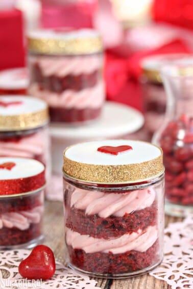 Red velvet cake in a jar with the lid on and multiple jars in the background.