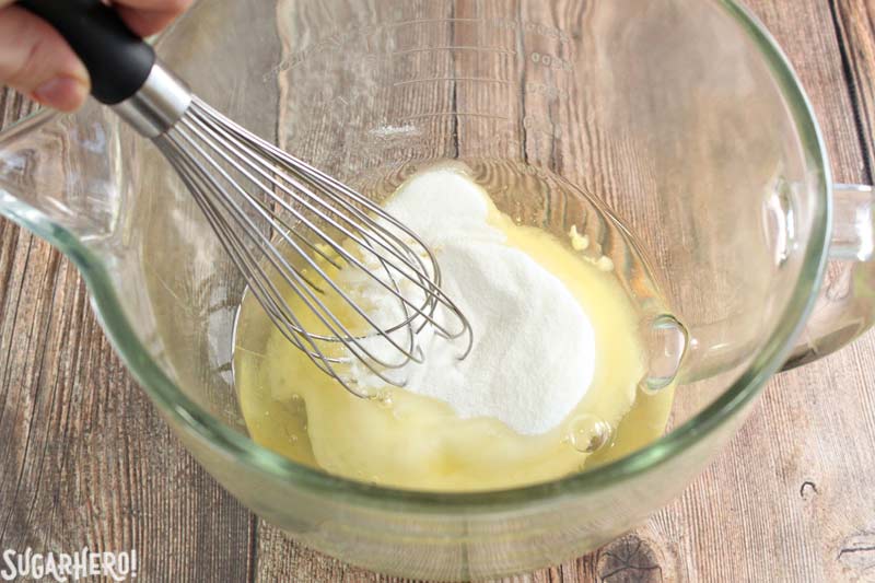 How to Make Swiss Meringue Buttercream - A photo of a whisk mixing the sugar and egg whites.  | From SugarHero.com