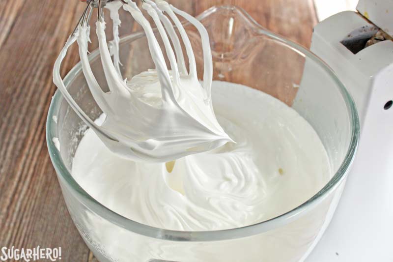 Swiss Meringue Buttercream is delicious, versatile, and the BEST frosting to use for layer cakes. Learn how to make it with this Swiss Meringue Buttercream recipe and photo tutorial! | From SugarHero.com How to Make Swiss Meringue Buttercream - A close up shot of the peak after the eggs and sugar have been mixed. | From SugarHero.com
