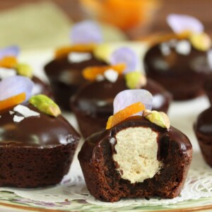 Nougat-Stuffed Brownie Bites on a floral plate and white doily with a bite removed from front brownie to show texture.