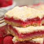 2 Raspberry Rhubarb Almond Bars next to a container of jam.