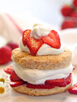Close up of strawberry shortcake topped with sliced strawberries and whipped cream.