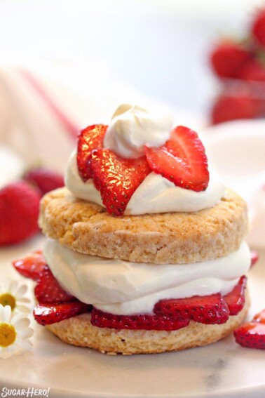 Close up of strawberry shortcake topped with sliced strawberries and whipped cream.