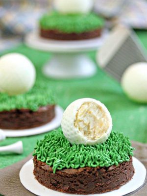 Close up of a Golf Ball Truffle and Putting Green Brownie with a bite removed from the truffle to show the interior and more brownies in the background.