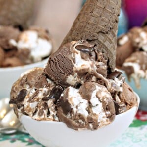 Close up of large scoops of Homemade Phish Food Ice Cream in a white bowl with a chocolate waffle cone on top.