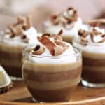 Layered Coffee Panna Cotta in glass cups with whipped cream and chocolate curls on top.