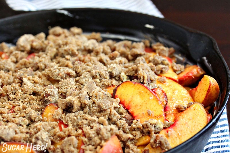 Sliced peaches in skillet with brown butter crumble on top