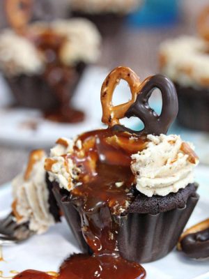 Chocolate-Dipped Pretzel Cupcakes oozing caramel sauce onto a white plate.