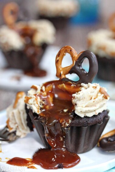 Chocolate-Dipped Pretzel Cupcakes oozing caramel sauce onto a white plate.