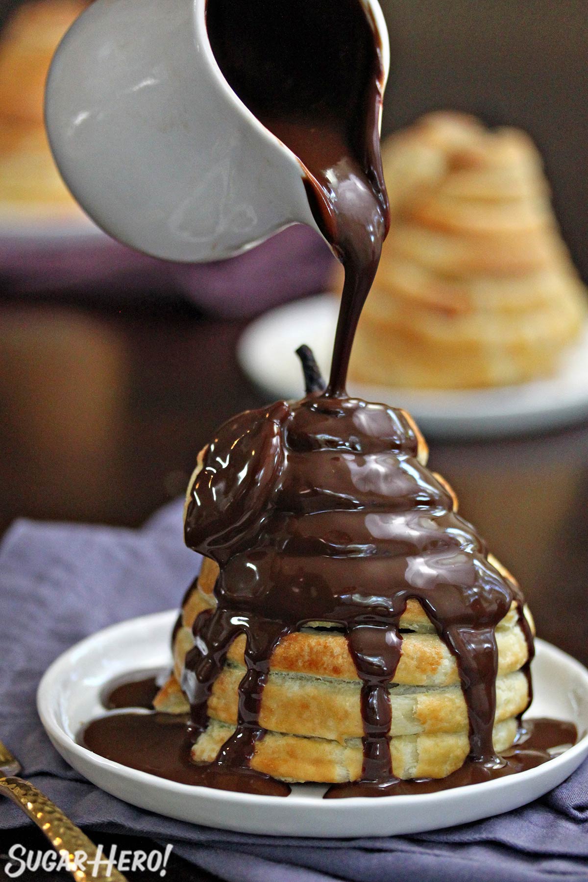 Puff Pastry-Wrapped Pear being drizzled with chocolate espresso sauce on a white plate.
