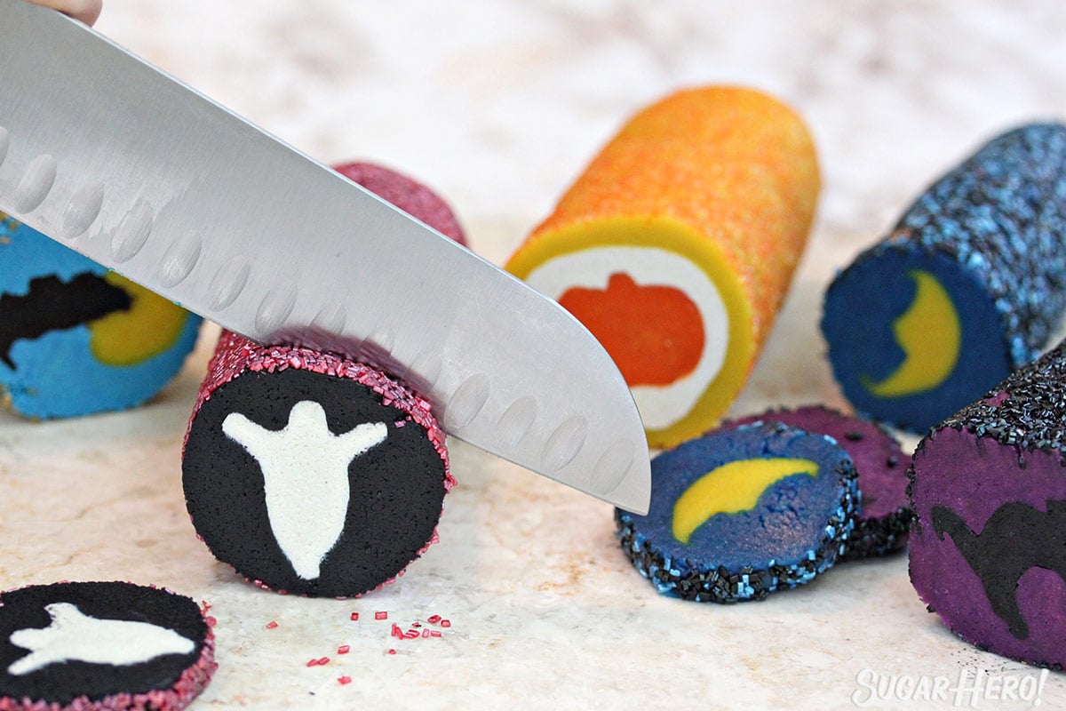 2 rolls of slice and bake Halloween cookies with a knife cutting into the ghost roll.