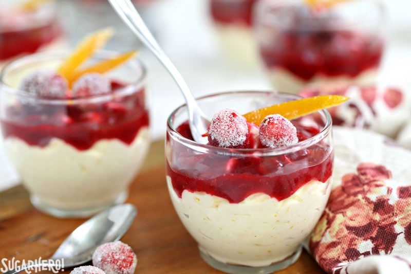 Orange Mousse with Cranberry Sauce- A shot of the mousse cups with a spoon in one. | From SugarHero.com