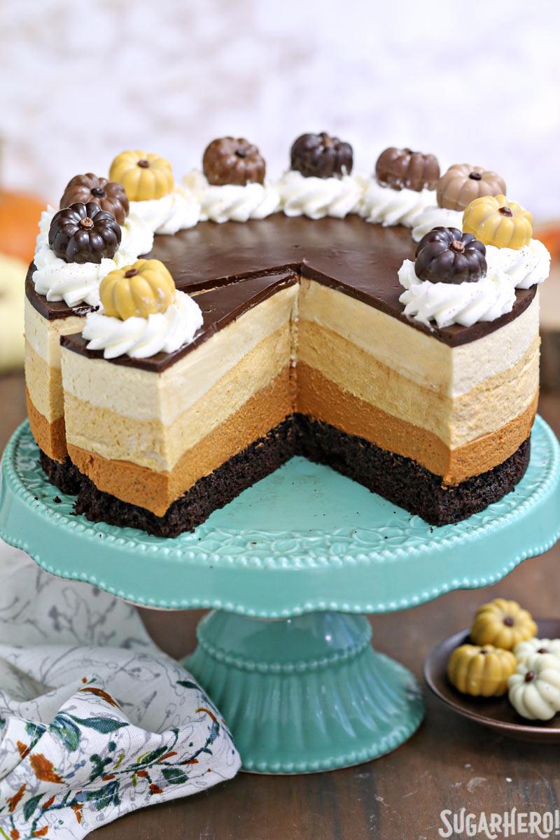 Pumpkin Chocolate Mousse Cake - A stunning 4-layer dessert with chocolate cake, cinnamon mousse, pumpkin-butterscotch mousse, and salted caramel mousse! Finished with a layer of shiny chocolate ganache and whipped cream, it’s a total show stopper! | From SugarHero.com Pumpkin Chocolate Mousse Cake - The cake displayed with pieces cut out. | From SugarHero.com