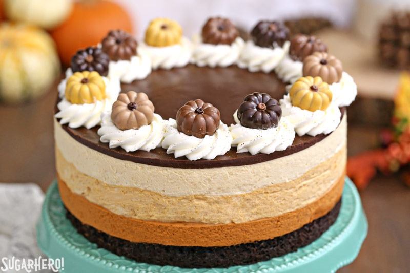 Pumpkin Chocolate Mousse Cake - A stunning 4-layer dessert with chocolate cake, cinnamon mousse, pumpkin-butterscotch mousse, and salted caramel mousse! Finished with a layer of shiny chocolate ganache and whipped cream, it’s a total show stopper! | From SugarHero.com Pumpkin Chocolate Mousse Cake - A closer shot of the cake with cute pumpkin toppers. | From SugarHero.com