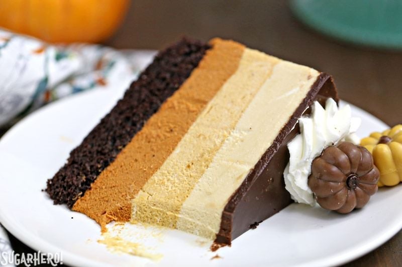 Pumpkin Chocolate Mousse Cake - A stunning 4-layer dessert with chocolate cake, cinnamon mousse, pumpkin-butterscotch mousse, and salted caramel mousse! Finished with a layer of shiny chocolate ganache and whipped cream, it’s a total show stopper! | From SugarHero.com Pumpkin Chocolate Mousse Cake - A slice with a bite taken out of it. | From SugarHero.com