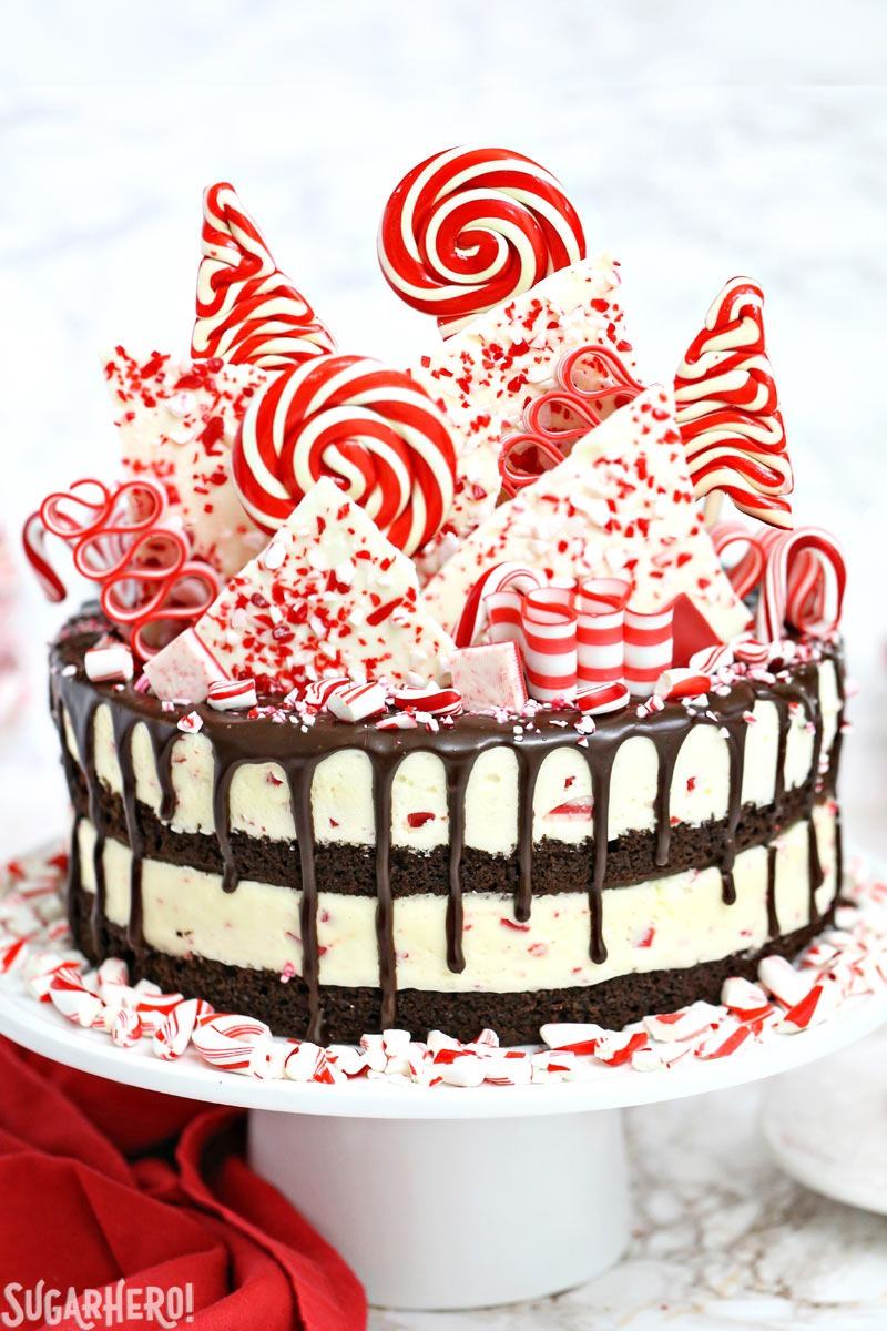 Candy Cane Mousse Cake on a white cake stand with peppermint pieces around the base