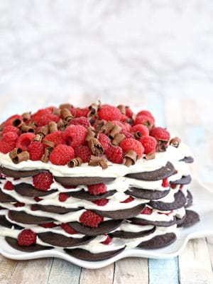 A Chocolate Raspberry No-Bake Cake on a white ruffled cake plate.