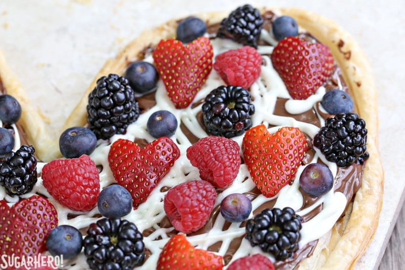 Nutella Puff Pastry Pizza is easy and gourmet. You’ll love the combination of buttery puff pastry, Nutella, white chocolate, and juicy fresh berries! | From SugarHero.com