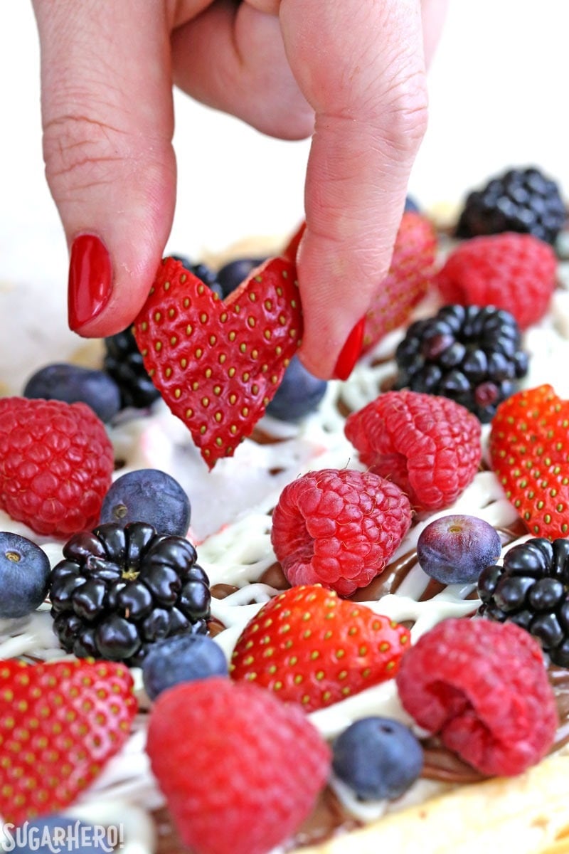 Nutella Puff Pastry Pizza is easy and gourmet. You’ll love the combination of buttery puff pastry, Nutella, white chocolate, and juicy fresh berries! | From SugarHero.com