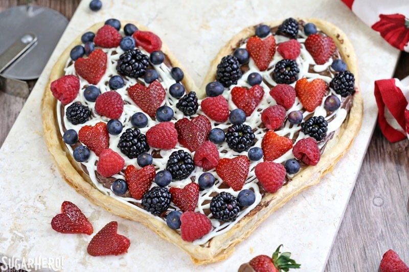 Nutella Puff Pastry Pizza is easy and gourmet. You’ll love the combination of buttery puff pastry, Nutella, white chocolate, and juicy fresh berries! | From SugarHero.com