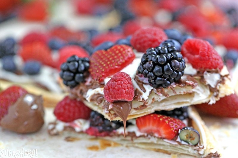 Nutella Puff Pastry Pizza is easy and gourmet. You’ll love the combination of buttery puff pastry, Nutella, white chocolate, and juicy fresh berries! | From SugarHero.com