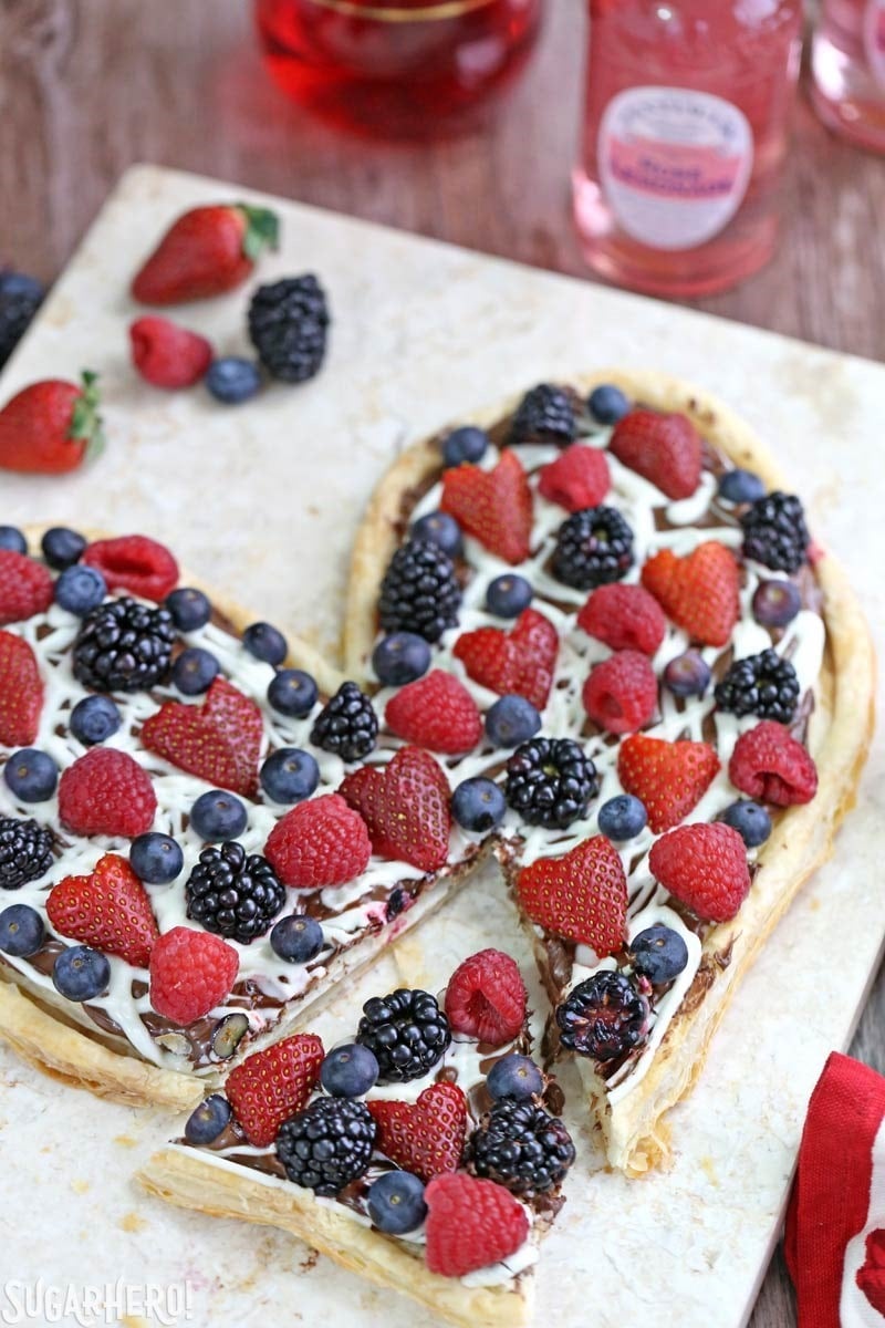 Nutella Puff Pastry Pizza is easy and gourmet. You’ll love the combination of buttery puff pastry, Nutella, white chocolate, and juicy fresh berries! | From SugarHero.com