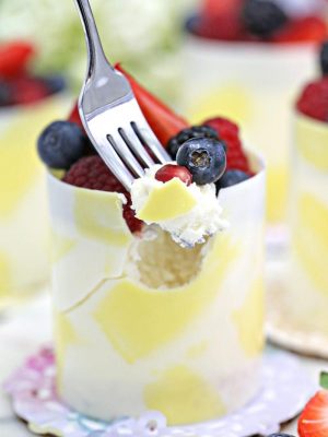 Close up of a Lemon Mousse Cake in a White Chocolate Shell on a small plate with a fork lifting out a bite.
