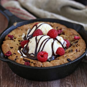 Close up of a Raspberry Truffle Skillet Cookie with a scoop of ice cream and chocolate sauce.