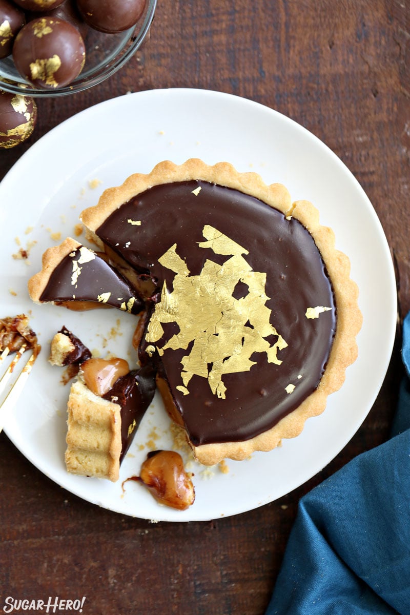 Overhead shot of Baileys Chocolate Caramel Tarts with gold leaf on top and several bites taken out of it