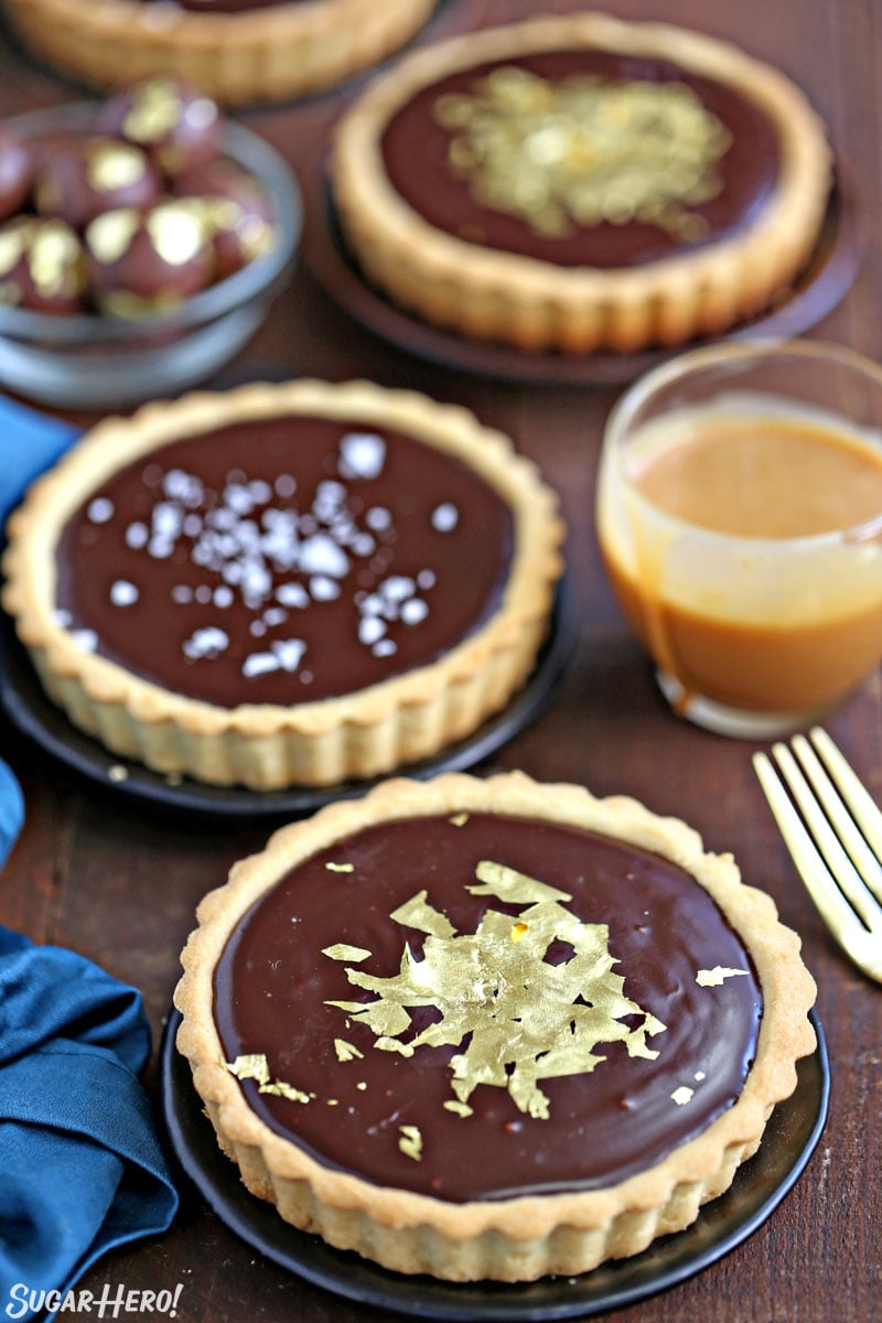 Three Baileys Chocolate Caramel Tarts topped with flaked sea salt and gold leaf