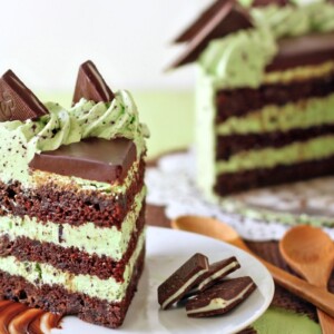 Mint chocolate chip layer cake on a white plate with the sliced cake in the background