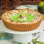 Side view of a Toasted Coconut Lime Meringue Tart on a white cake plate.
